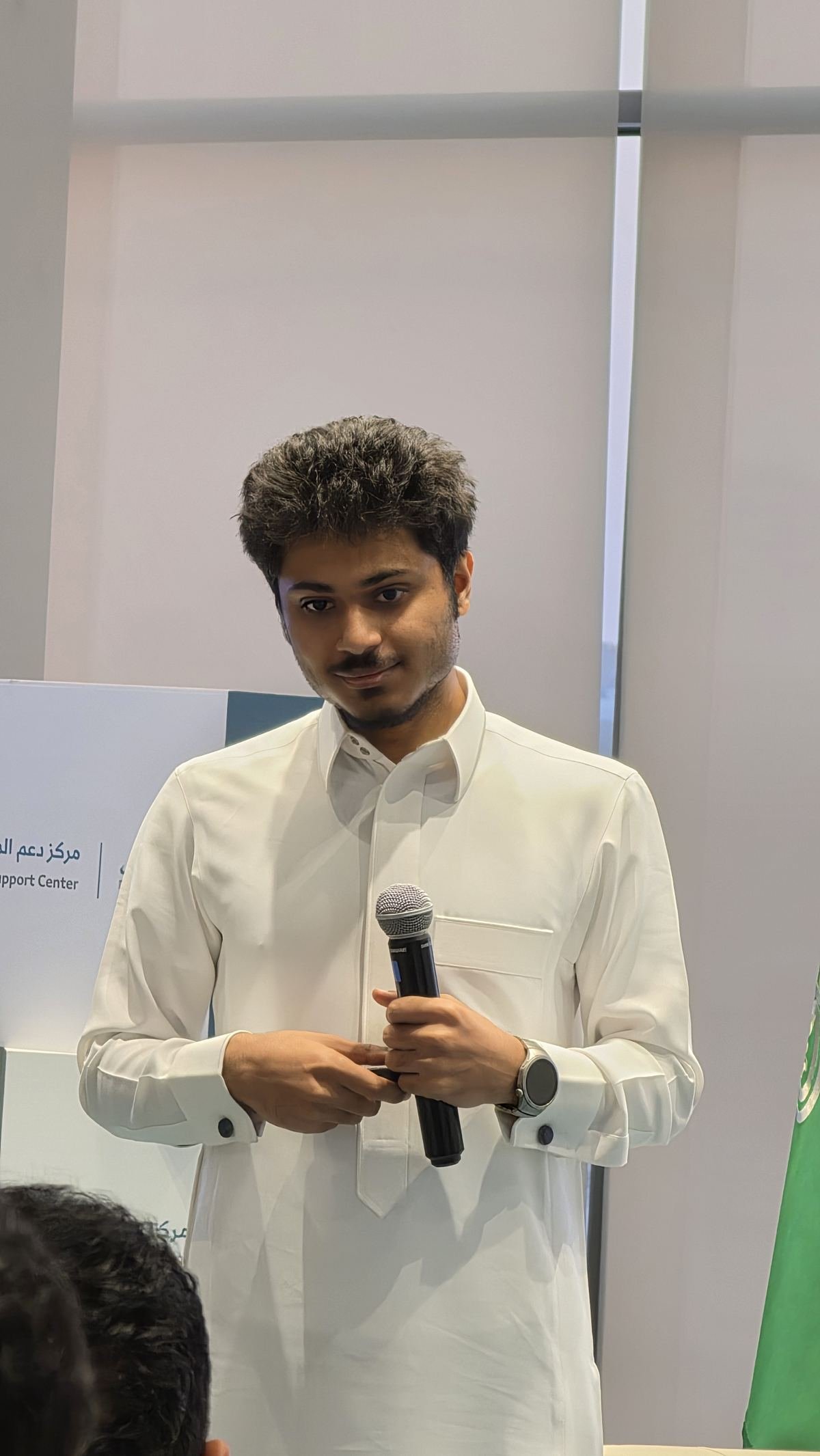رضا العايش ممسكًا بالميكروفون في مركز دعم المنشآت بالخبر، أثناء ورشة بناء قسم التسويق في 15 يونيو 2026.